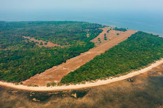 A drone view of Hermana Mayor’s grass airstrip, stretching through woodland beside the coast.